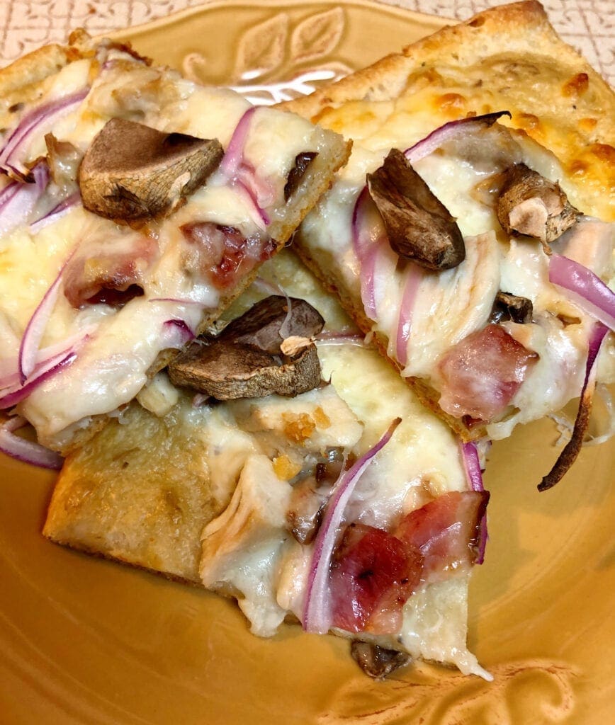 Three Pieces of Chicken Bacon Alfredo Pizza Served on a Plate