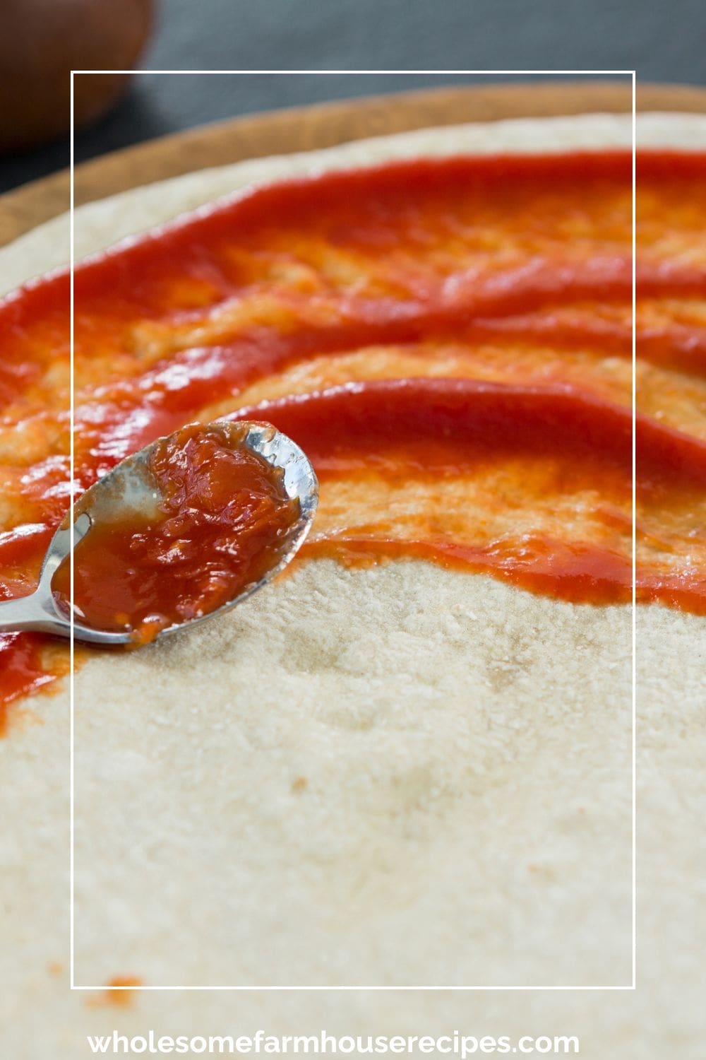 spreading pizza sauce on dough